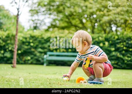 Très petit enfant jouant avec une voiture jouet dans le parc Banque D'Images