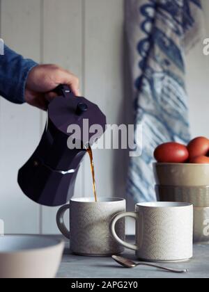 Un homme qui verse du café dans une tasse Banque D'Images