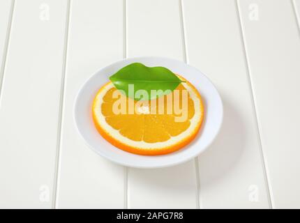 Fine tranche d'orange frais sur la plaque blanche Banque D'Images