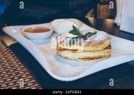 crêpes moelleuses avec sirop d'érable servies sur une plaque blanche et décorées de feuilles de menthe Banque D'Images