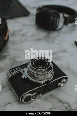 Prise de vue verticale d'un appareil photo, d'un casque et d'un ordinateur portable placés sur une table en marbre Banque D'Images