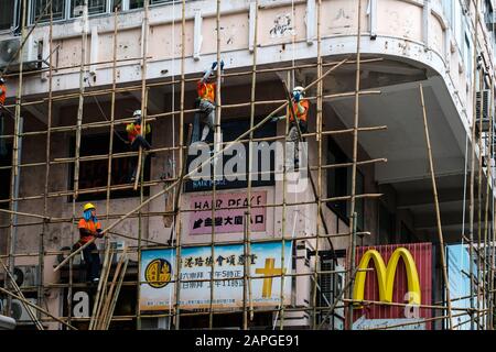 Hong Kong, novembre 2019: Travailleurs sur le chantier de construction de l'échafaudage en bambou sur la façade de maison à Hong Kong Banque D'Images