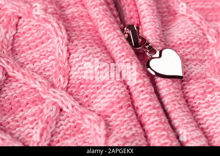 Glissière avec forme de coeur dans la fermeture éclair sur les vêtements en tissu rose laolien. Saint Valentin matériel de fond. Concept d'amour. Signe d'amour abstrait Banque D'Images