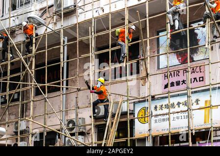 Hong Kong, novembre 2019: Travailleurs sur le chantier de construction de l'échafaudage en bambou sur la façade de maison à Hong Kong Banque D'Images