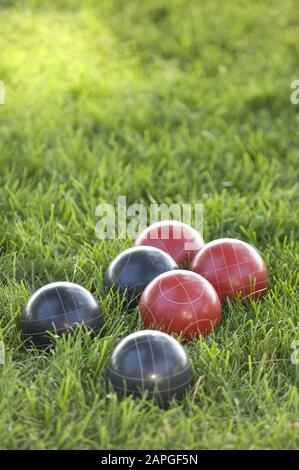 Image verticale de boules de bocce colorées sur la pelouse sous la lumière du soleil avec un arrière-plan flou Banque D'Images