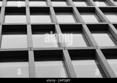 Prise de vue en niveaux de gris à faible angle d'un immeuble de bureaux avec fenêtres Banque D'Images