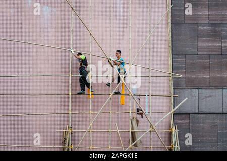 Hong Kong, novembre 2019: Travailleurs sur le chantier de construction de l'échafaudage en bambou sur la façade de maison à Hong Kong Banque D'Images