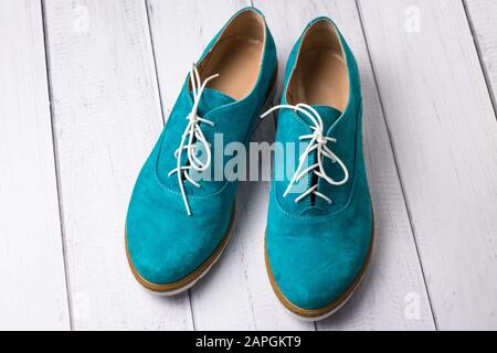 Paire de chaussures en daim vert décontracté avec lacets sur fond en bois. oxfords turquoise pour femme, chaussure oxford Banque D'Images