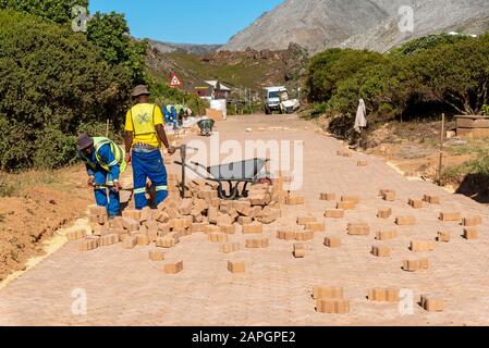 Rooiels, Cap Occidental, Afrique Du Sud. Décembre 2019. Travailleurs qui pontent une route en brique dans le petit hameau de Rooiels. Banque D'Images