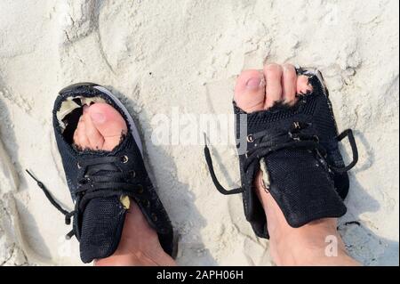 Un homme portant de vieilles chaussures portées sur les pieds avec des trous Banque D'Images