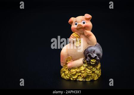 Figurine d'une petite piggie assise sur une pile d'or, fond noir Banque D'Images