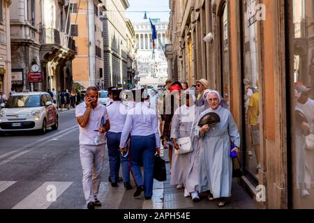 Un groupe de religieuses passant par un groupe de cadets de l'armée féminine dans une rue de Rome Banque D'Images