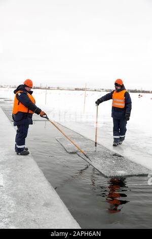 Les employés radeau des blocs de glace le long d'une chaîne coupée un lac gelé Banque D'Images