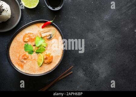 Tom Yam kung soupe thaï aux crevettes, fruits de mer, le lait de coco, le piment et le riz en noir bol. Vue de dessus. Orientation horizontale. C'Asie Banque D'Images