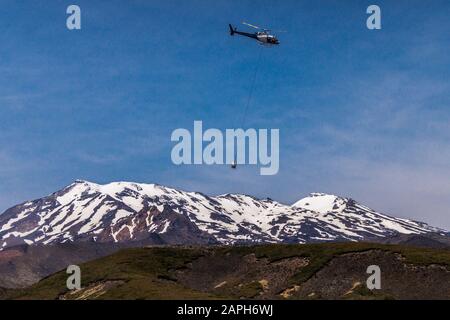 Hélicoptère en service public de nettoyage des toilettes en vol au-delà du mont Ruapehu, parc national de Tongariro, île du Nord, Nouvelle-Zélande, Banque D'Images