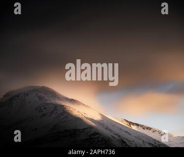 Des nuages spectaculaires et un soleil doré sur la neige Ben Nevis - la plus haute montagne du Royaume-Uni Banque D'Images