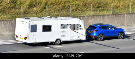 Vue du dessus et du dos de la voiture d'écloserie Blue Nissan et conducteur remorquage blanc Lunar venus 570 caravane de vacances longeant l'autoroute M25 Angleterre Royaume-Uni Banque D'Images