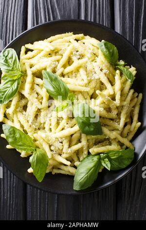 Pâtes italiennes au trofie avec pesto au basilic et gros plan au parmesan dans une assiette sur la table. Vue verticale du dessus Banque D'Images