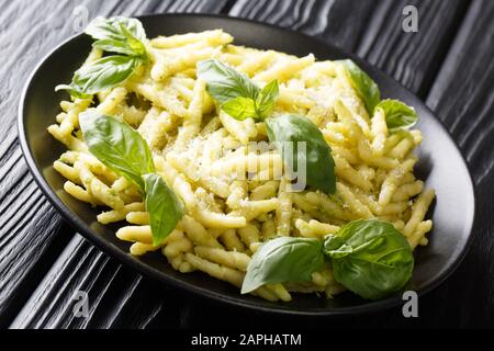 Portion de pâtes au trofie avec pesto au basilic vert et gros plan de parmesan dans une assiette sur la table. Horizontale Banque D'Images