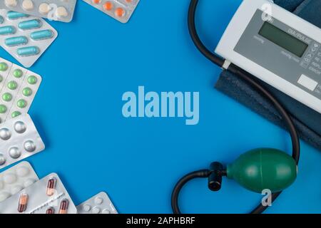 Sonomètre électronique, dispositif de mesure de la pression. Pilules de couleur. Seringues avec le médicament. Fond bleu. Banque D'Images