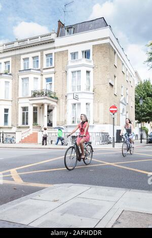 Deux cyclistes traversant une intersection dans Earls court sur la route à vélo Quietway 15 Banque D'Images