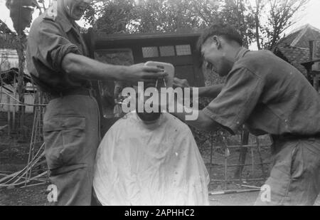 2ème Field Company Army Genie Gekbrung Soekaboemi Description: Le coiffeur sur le terrain ne peut pas offrir à sa clientèle un confort excessif. Le Sergent Dierdorp d'Amsterdam manipule avec des miroirs pour donner à la victime, le Sergent Vaille de Zutphen une idée du changement profond que sa tête de cheveux subit. Date : Septembre 1947 Lieu : Indonésie, Antilles Néerlandaises De L'Est Banque D'Images