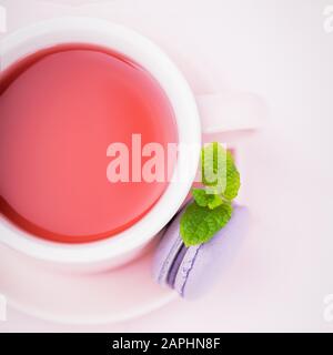 Thé aux fruits, macaron blackberry ou macaron avec feuille de menthe sur fond rose pâle, espace de copie Banque D'Images