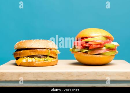 le hamburger classique et le hamburger alimentaire à base de fruits et de baies se trouvent à côté d'une planche en bois Banque D'Images