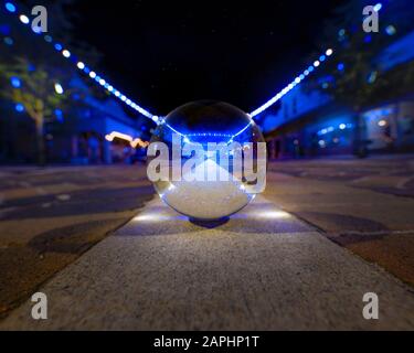 Une petite rue principale de la ville pendant la saison des vacances se reflète dans un "lensball". Banque D'Images