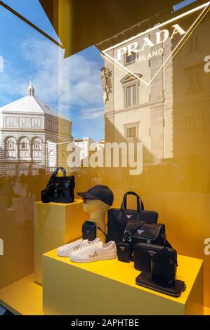 Florence, Italie - 2020, 19 janvier : porte-monnaie et chaussures dans une boutique de mode Prada. Paysage urbain reflété dans les fenêtres. Banque D'Images