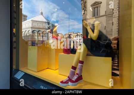 Florence, Italie - 2020, 19 janvier : porte-monnaie, chaussures et vêtements pour femmes dans une boutique de mode Prada. Paysage urbain reflété dans les fenêtres. Banque D'Images