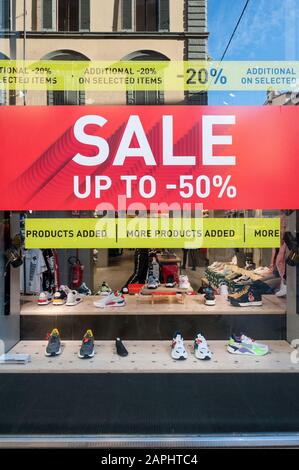 Florence, Italie - 2020, Jan 19: Bannière de vente de chaussures sur une vitrine boutique. Bâtiments de la ville reflétés dans la fenêtre. Banque D'Images