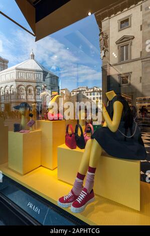 Florence, Italie - 2020, 19 janvier : porte-monnaie, chaussures et vêtements pour femmes dans une boutique de mode Prada. Paysage urbain reflété dans les fenêtres. Banque D'Images