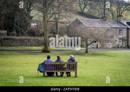 Trois personnes se sont assises sur un banc de parc à Langcliffe près de s'établir pour déjeuner Banque D'Images