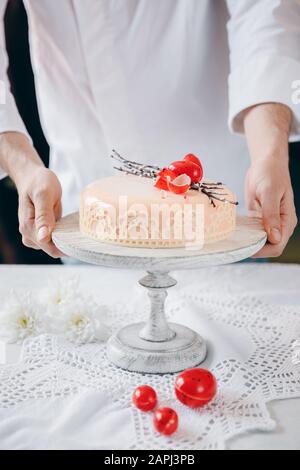 Le chef masculin met le kulich de gâteau de Pâques avec des œufs au chocolat et du saule sur la table Banque D'Images