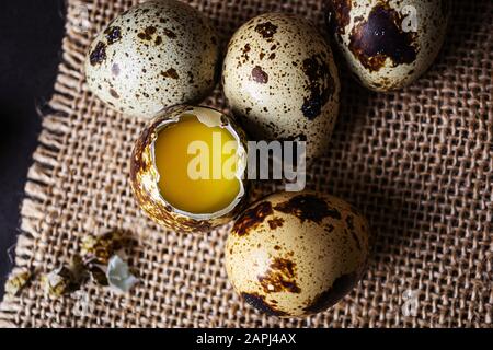 Œufs de Quail, un ouvert, le reste entier. Fond sombre, toile de fond. Vue de dessus. Le concept de produits naturels organiques, de protéines alimentaires. Banque D'Images