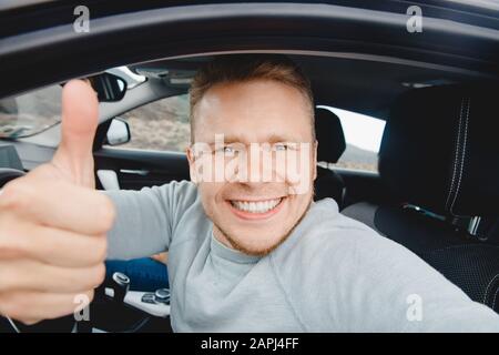 Heureux homme conducteur acheteur voiture regardant l'appareil photo et prendre la photo selfie, beau sourire. Concept de préparation pour le voyage sur route, la location d'auto Banque D'Images