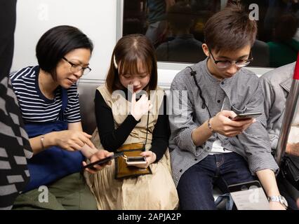 Hong Kong MTR - les gens en transport sur le train de transport en commun de Hong Kong utilisant leurs téléphones mobiles, Hong Kong Asia Banque D'Images