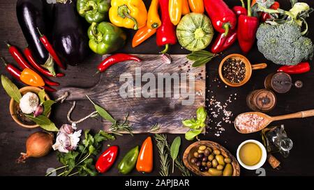 couleurs et saveurs de différents types de légumes et ingrédients sur la table et le tableau de découpe du bois brut Banque D'Images