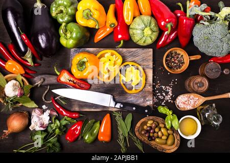 couleurs et saveurs de différents types de légumes et ingrédients sur la table et le tableau de découpe du bois brut Banque D'Images