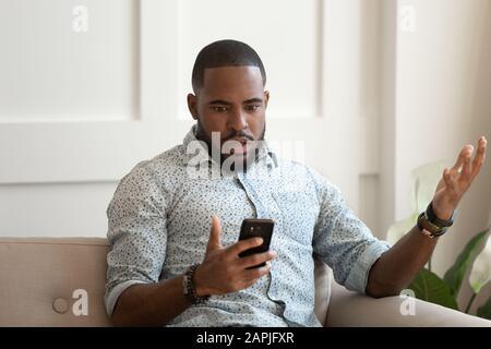 L'homme africain tient le téléphone portable lire sms se sent choqué Banque D'Images