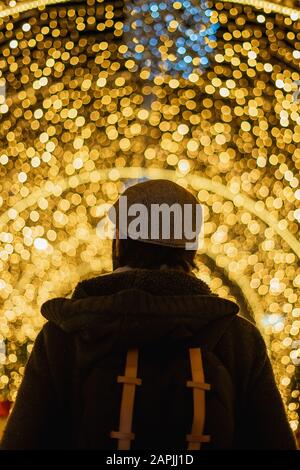 Homme vu de derrière avec des lumières de noël en arrière-plan Banque D'Images