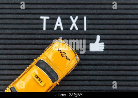 Il suffit de concevoir un modèle jaune jouet taxi cabine modèle avec inscription DES lettres DE TAXI mot sur fond noir. Symbole automobile et transport. Concept d'idée de service urbain de livraison de trafic urbain. Espace de copie Banque D'Images