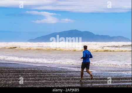 Île de Kāpiti vue de la plage de Ōtaki, avec un homme en marche, île du Nord, Nouvelle-Zélande Banque D'Images