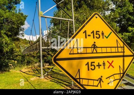 Signe de danger sur le pont suspendu piétonnier au-dessus de la rivière Ōtaki, Parc forestier de Tararua, Ōtaki Forks, Île du Nord, Nouvelle-Zélande Banque D'Images