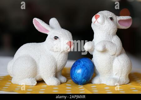 Des décorations de Pâques colorées et joyeuses sur une table. Gros plan image couleur de deux lapins de Pâques en céramique et des œufs de Pâques peints colorés. Banque D'Images