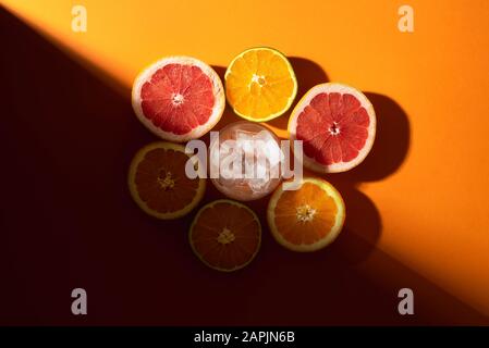 Les agrumes sont coupés en deux et les glaçons en verre sur fond orange, en plein soleil. Préparation du concept de cocktail d'été froid. Faire une boisson tropicale Banque D'Images