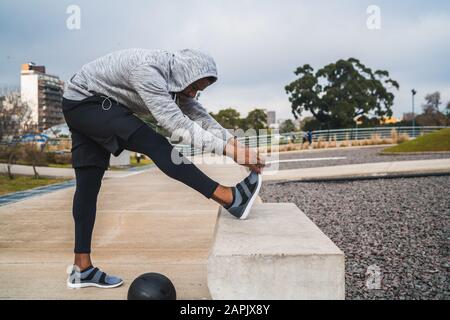 Portrait d'un homme athlétique étirant les jambes avant de faire de l'exercice à l'extérieur. Sport et mode de vie sain. Banque D'Images