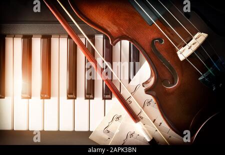 ARC de violon et partitions de musique sur les touches du piano. Concept d'interprétation de la musique de piano et des instruments à cordes. Vue de dessus. Composition horizontale. Banque D'Images