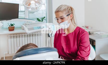 Une dentiste de bureau dentaire traite les dents avec un patient enfant. Banque D'Images